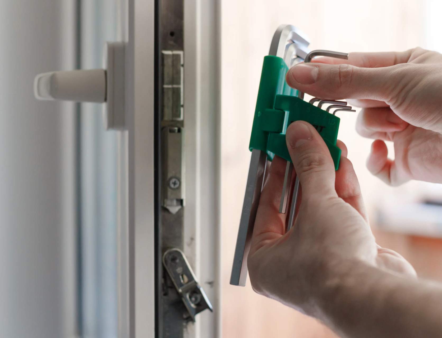 door-1 A person selects an Allen key from a set near a white door lock.